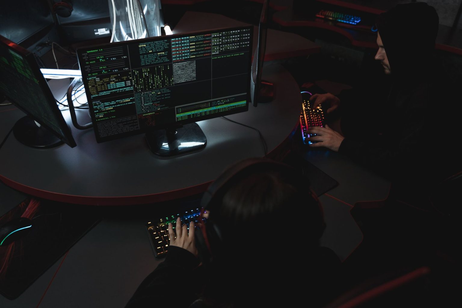 Equipe trabalha diante de computadores em uma sala escura, em atividade relacionada à segurança cibernética.