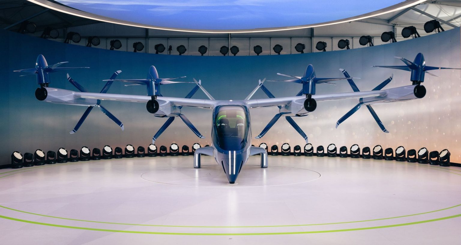 Protótipo de aeronave elétrica futurista com hélices, exibido em ambiente interno.
