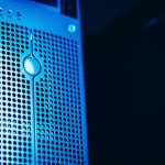 Sala de data center com racks de servidores iluminados em azul.